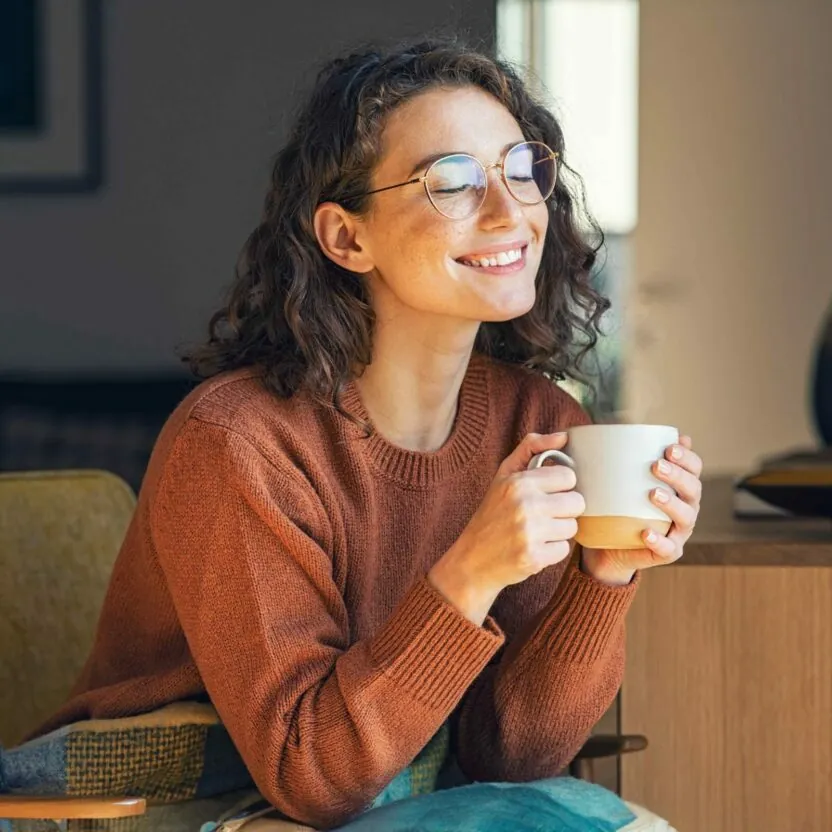 woman-drinking-coffee-1326419180 Happy young woman drinking a cup of tea or coffee in an autumn morning.