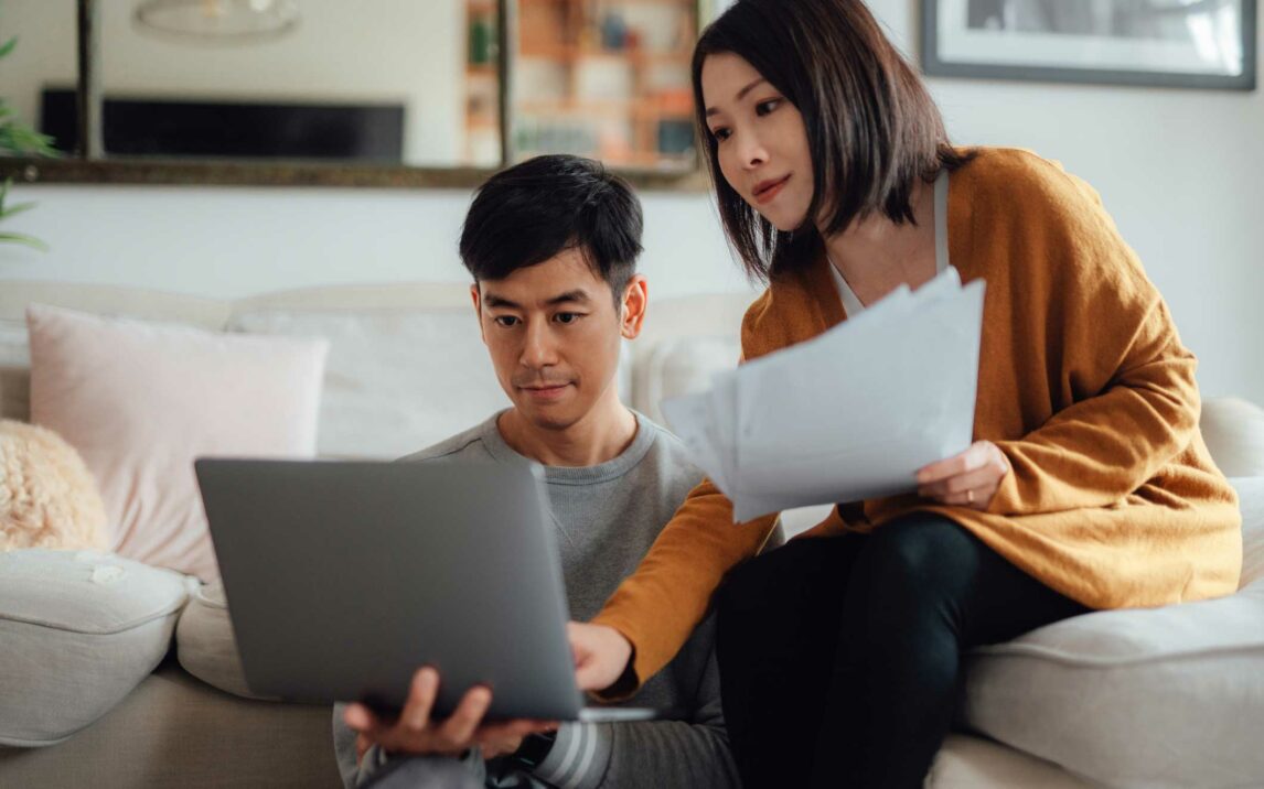 young couple discussing over financial bills while using laptop on sofa young couple discussing over financial bills while using laptop on sofa